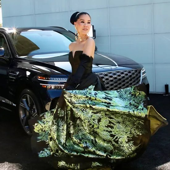 제네시스 SUV 앞에 서 있는 정장 차림의 여성